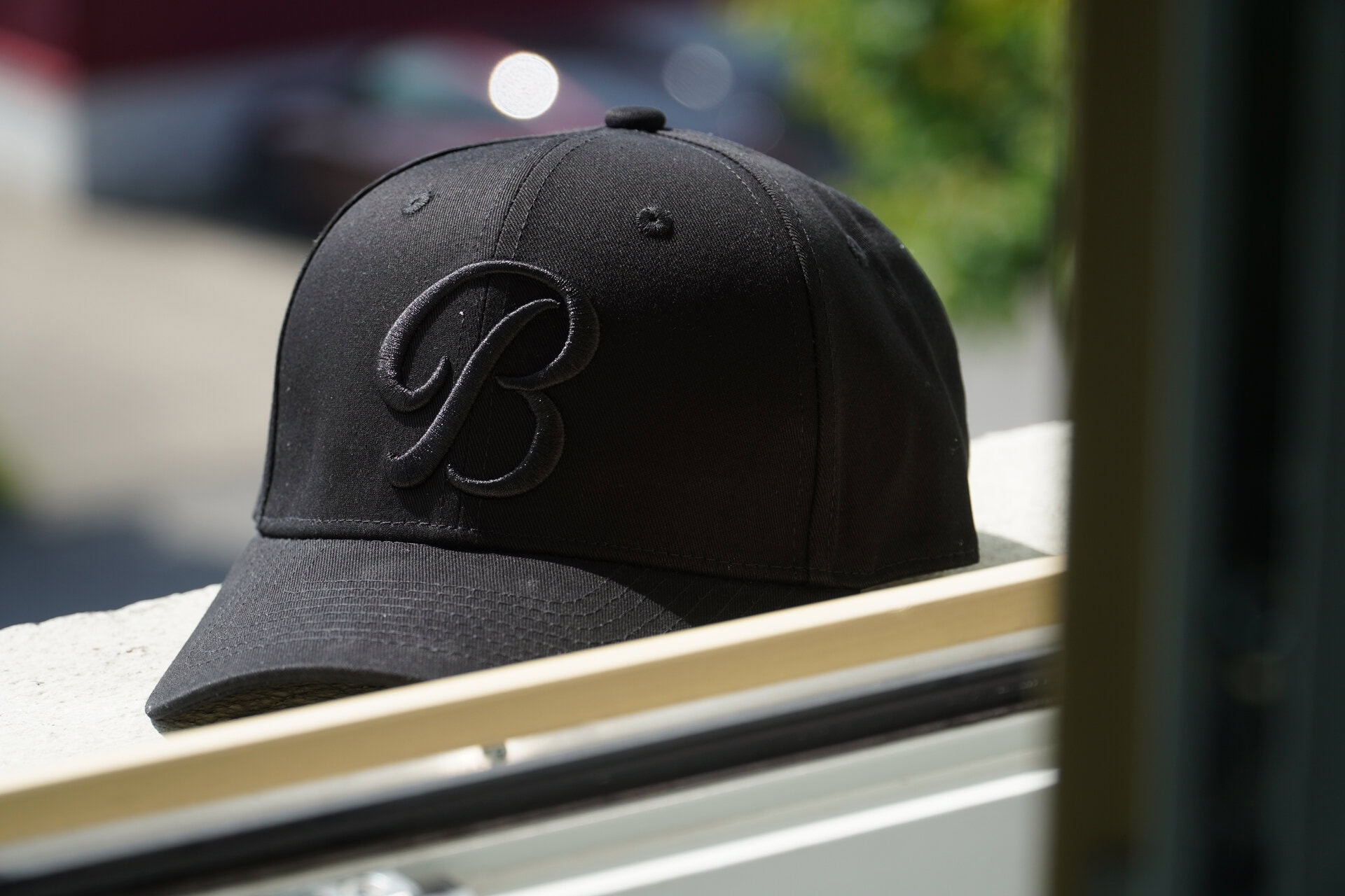 Schwarze Baseballkappe mit Schriftzug auf Fensterbrett