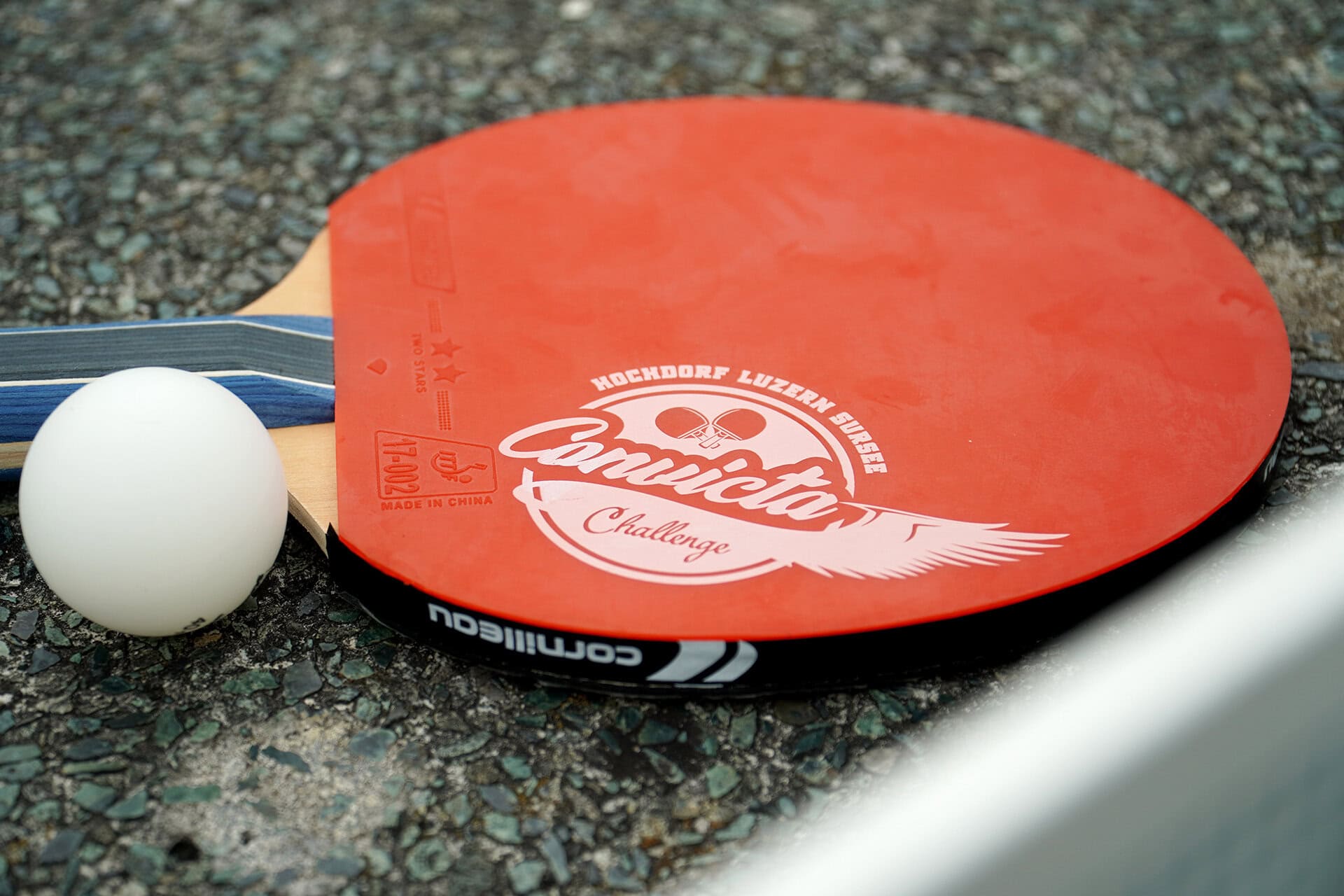 Tischtennisschläger und Ball auf Asphaltboden.