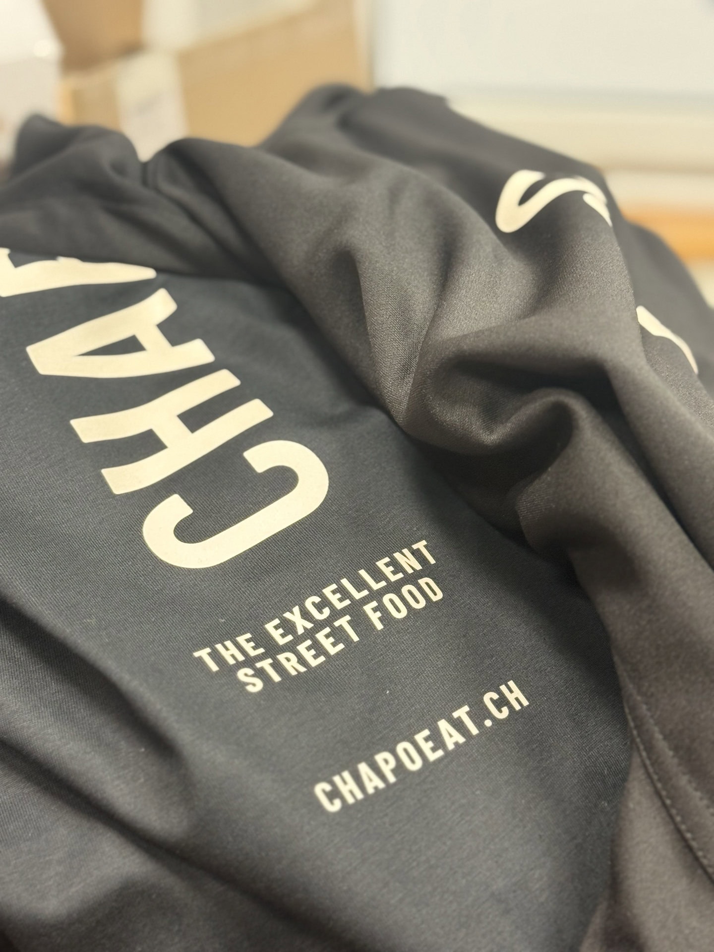 Schwarzer Stoff mit weißem Text und Logo.